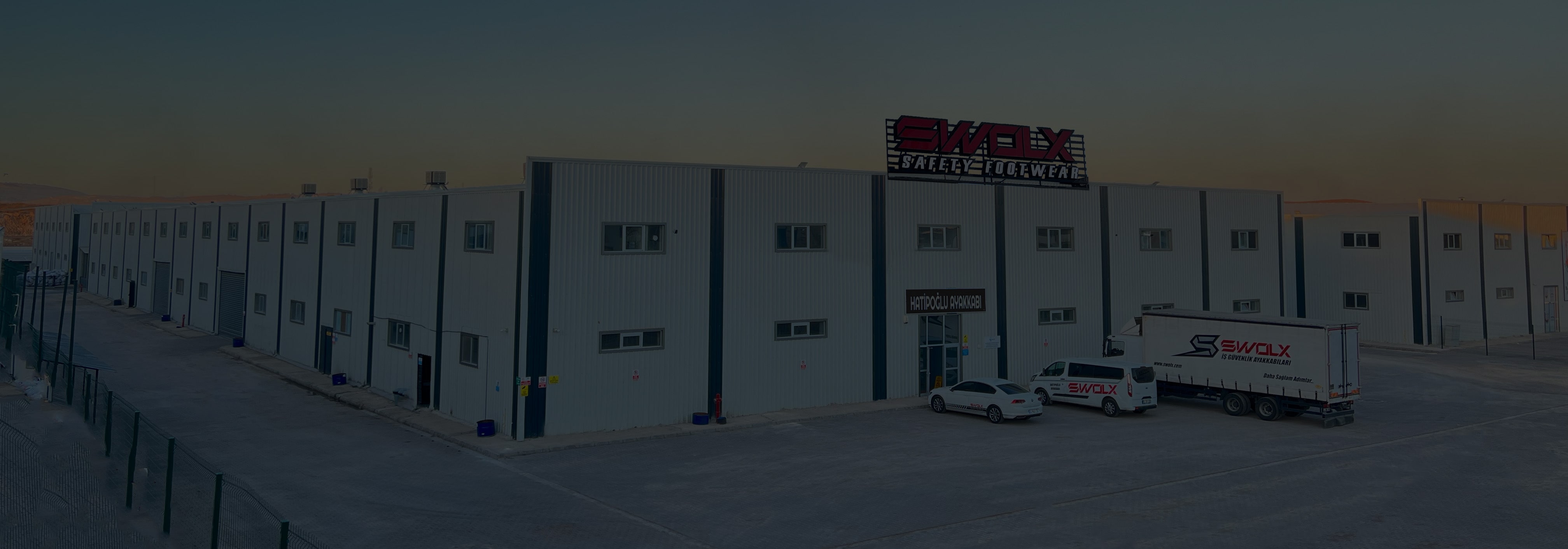 Factory building with SWOLX sign and branded delivery vehicles